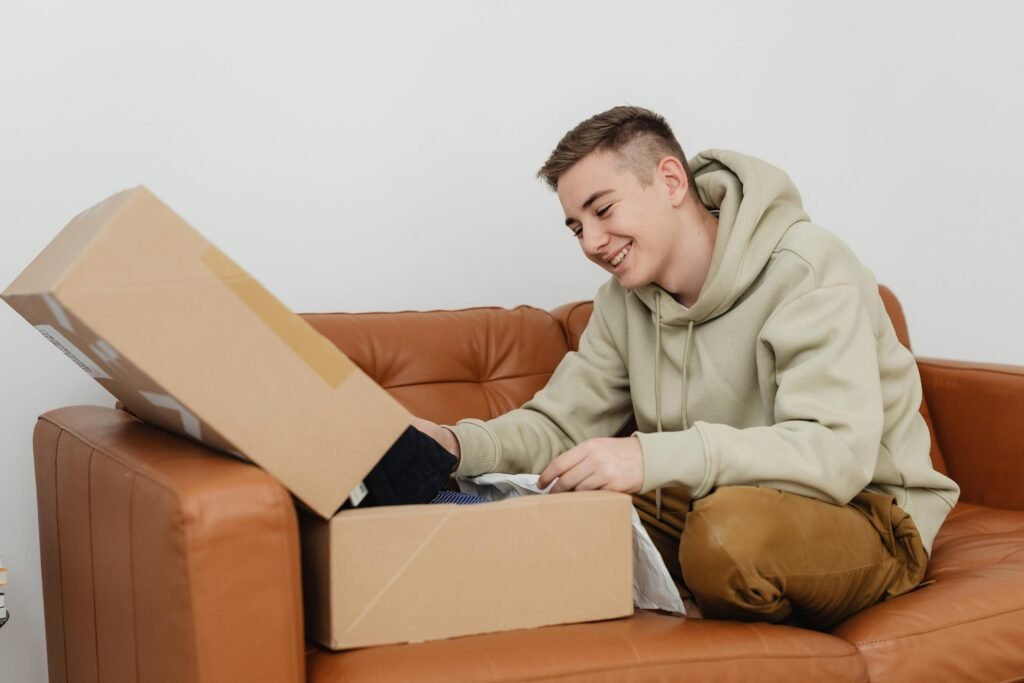 Man opening a package on a couch, representing long-distance gifts for him and thoughtful long-distance boyfriend gift ideas.